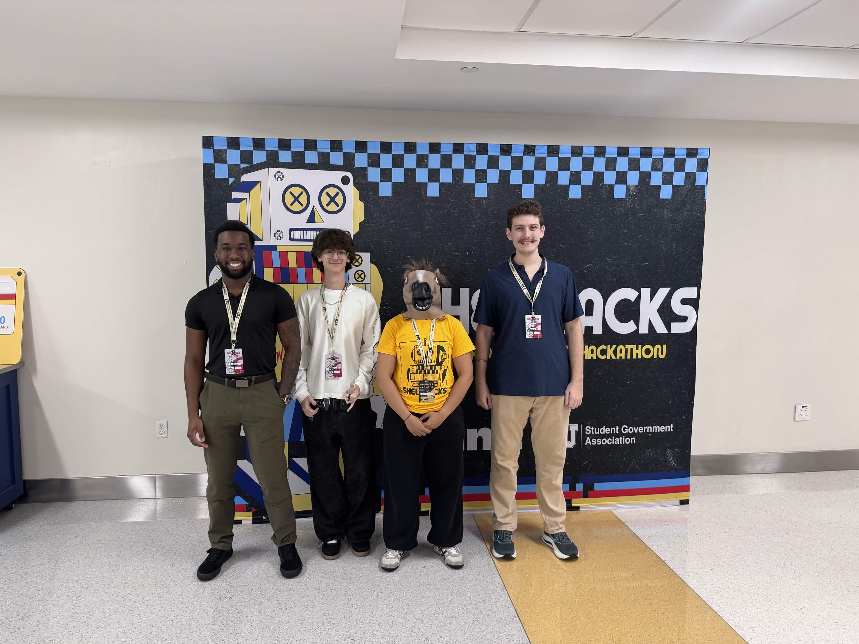 The JARVIS team in front of the ShellHacks wall